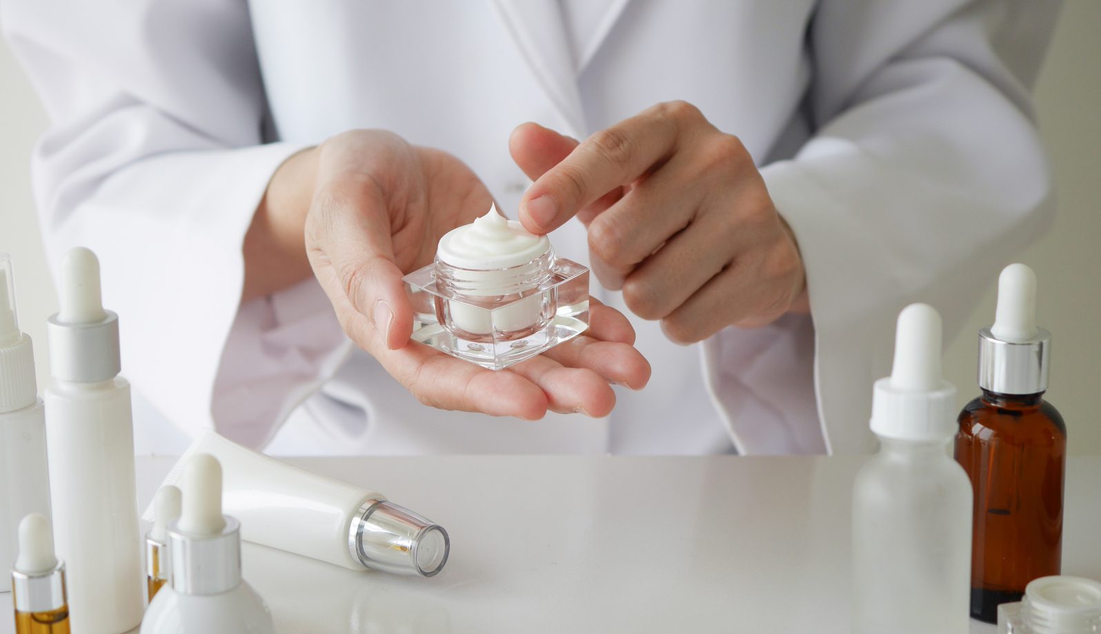 474 (2) Hands holding a small jar of cream, showing skincare application.