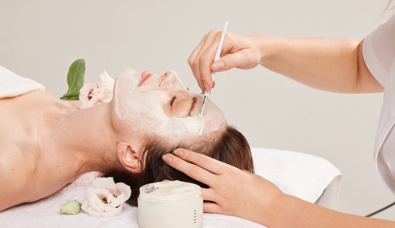 Woman receiving a facial mask treatment at a spa.