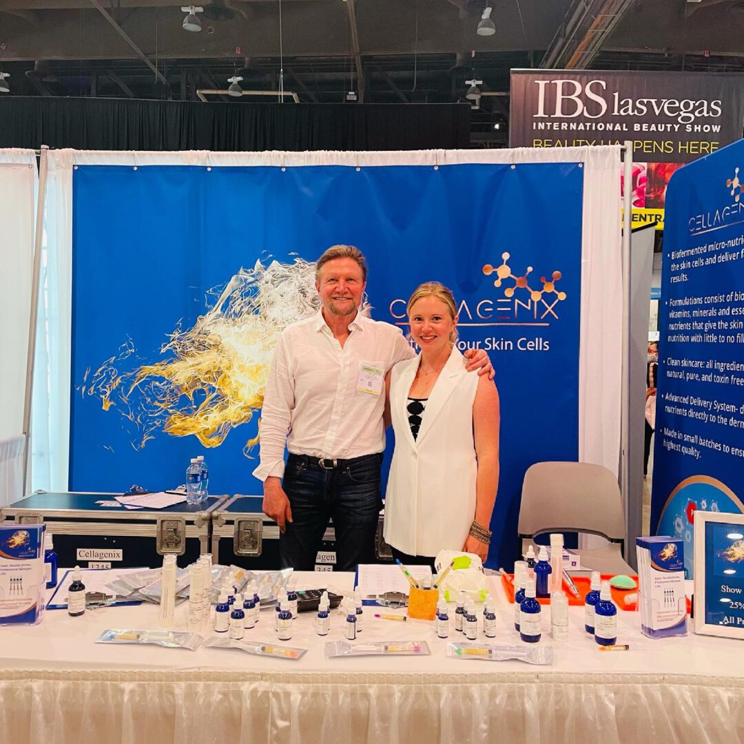 Two people at a professional booth with a colorful backdrop and product displays.